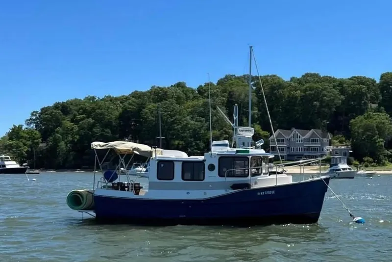 The Image of 2007 Ranger Tugs R-25 boat anchored in a scenic bay with waterfront homes. - 1
