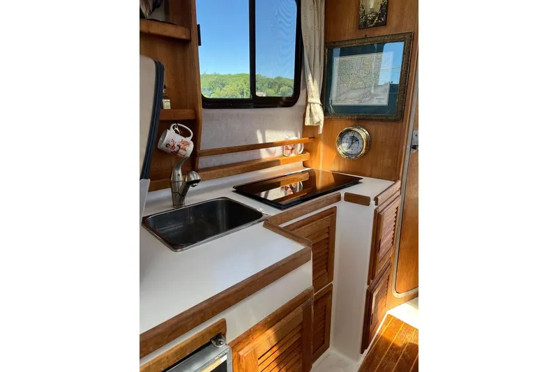 Slide: The Image of 2007 Ranger Tugs R-25 interior kitchen with sink, stove, and wooden cabinetry. - 10