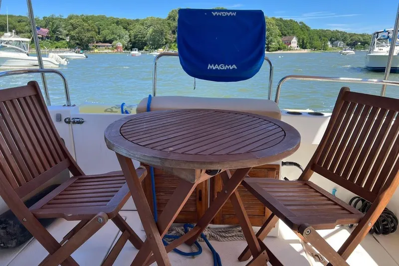 Slide: The Image of 2007 Ranger Tugs R-25 boat deck with wooden table and chairs, scenic waterfront view. - 4