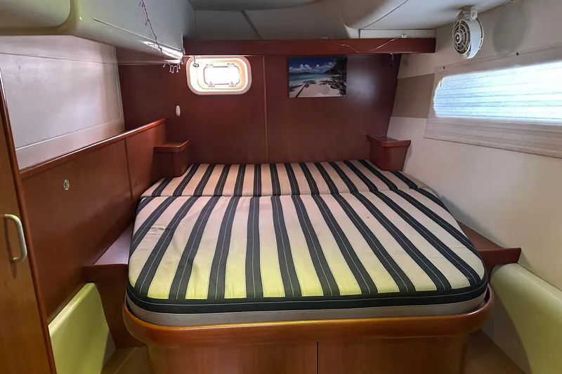 Slide: The Image of 2011 Robertson & Caine Leopard 46 yacht cabin with striped bedding and wooden interior. - 26