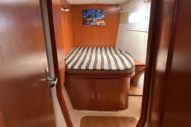 Slide: The Image of 2011 Robertson & Caine Leopard 46 cabin interior with striped bedding and wooden finish. - 5