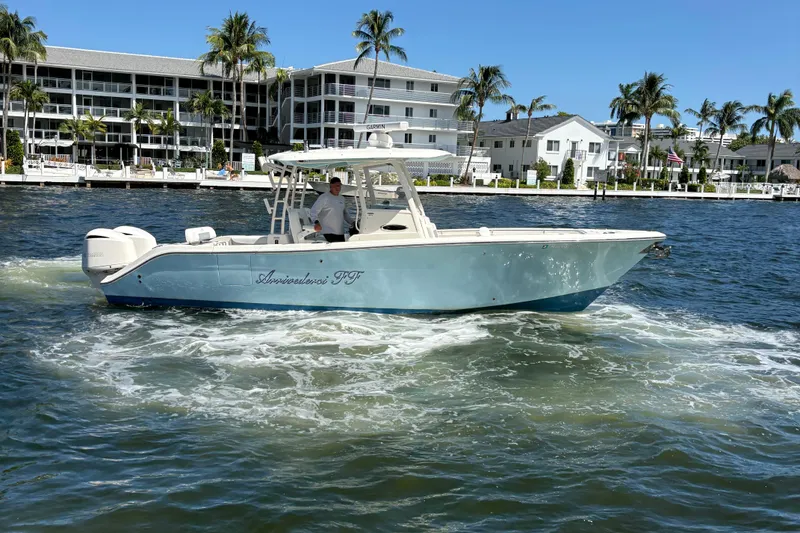 Slide: The Image of 2018 Cobia 301 Center Console boat cruising near waterfront homes and palm trees. - 10