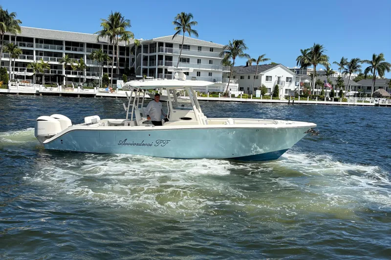 Slide: The Image of 2018 Cobia 301 Center Console boat cruising near waterfront homes and palm trees. - 11