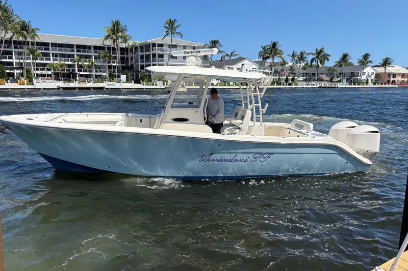 Slide: The Image of 2018 Cobia 301 Center Console boat on water near palm trees and buildings. - 14