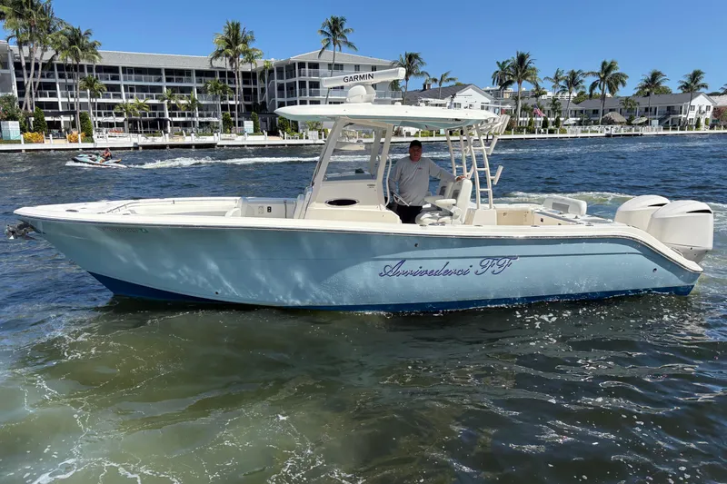 Slide: The Image of 2018 Cobia 301 Center Console boat on water, with palm trees and buildings in background. - 15
