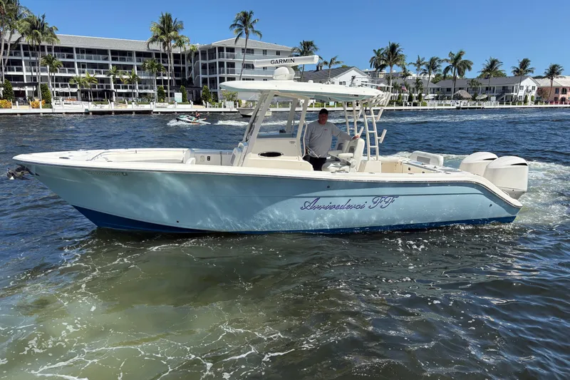 Slide: The Image of 2018 Cobia 301 Center Console boat cruising on a sunny day near waterfront buildings. - 16