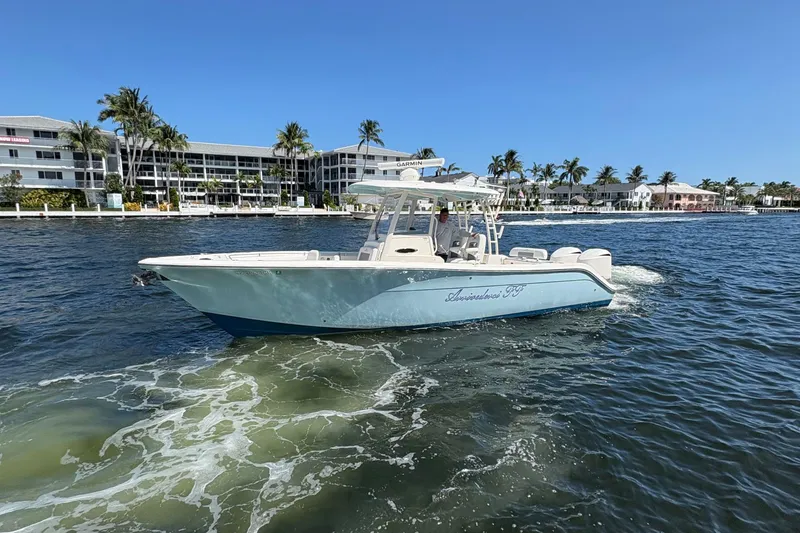 Slide: The Image of 2018 Cobia 301 Center Console boat cruising near waterfront buildings and palm trees. - 18