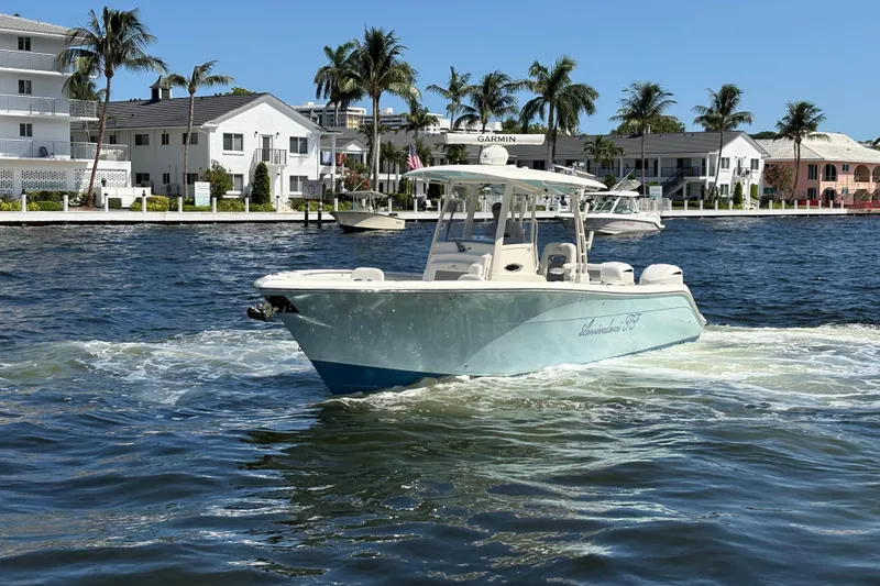 Slide: The Image of 2018 Cobia 301 Center Console boat cruising on a sunny waterfront with palm trees. - 5