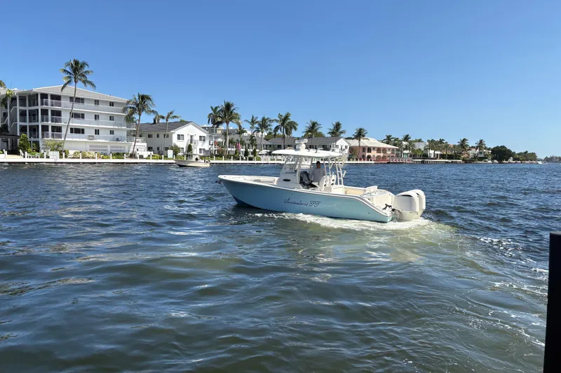 Slide: The Image of 2018 Cobia 301 Center Console boat cruising on a sunny waterfront with palm trees. - 6
