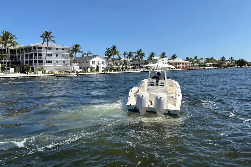 Slide: The Image of 2018 Cobia 301 Center Console boat cruising near waterfront homes and palm trees. - 7