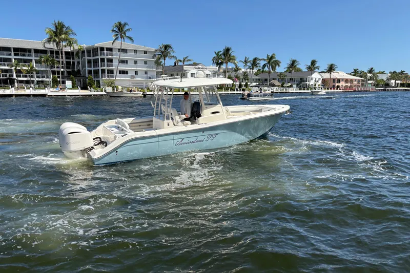 Slide: The Image of 2018 Cobia 301 Center Console boat cruising near waterfront homes and palm trees. - 8
