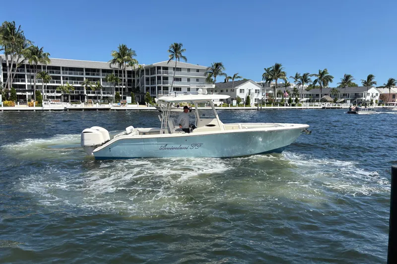 Slide: The Image of 2018 Cobia 301 Center Console boat cruising on a sunny waterfront with palm trees. - 9