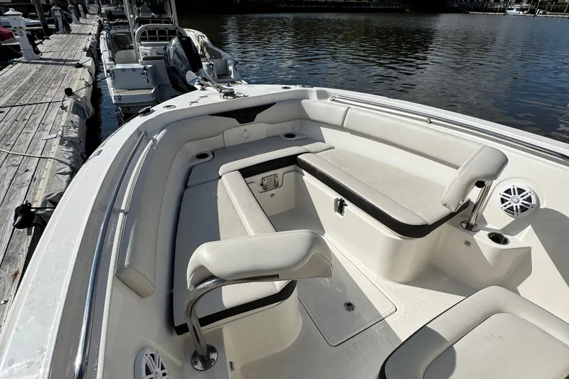 Slide: The Image of 2024 Sailfish 241 CC boat interior with cushioned seating and cup holders at dock. - 13
