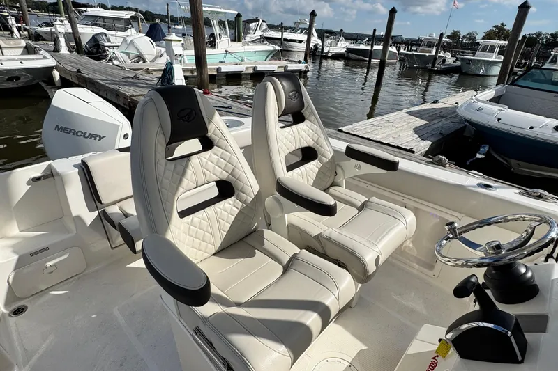Slide: The Image of 2024 Sailfish 241 CC boat interior with luxurious seating and steering wheel at marina. - 16