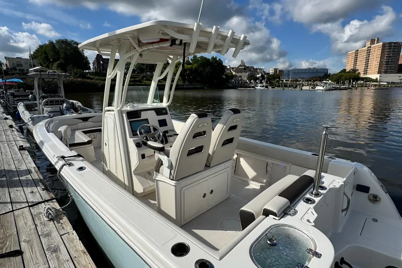 Slide: The Image of 2024 Sailfish 241 CC boat docked by a scenic waterfront under a cloudy sky. - 24