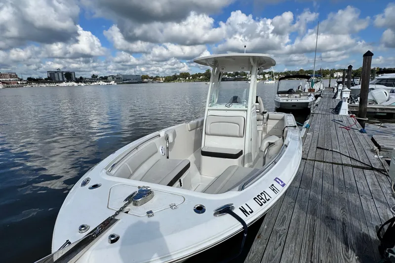 Slide: The Image of 2024 Sailfish 241 CC boat docked at a marina under a partly cloudy sky. - 25