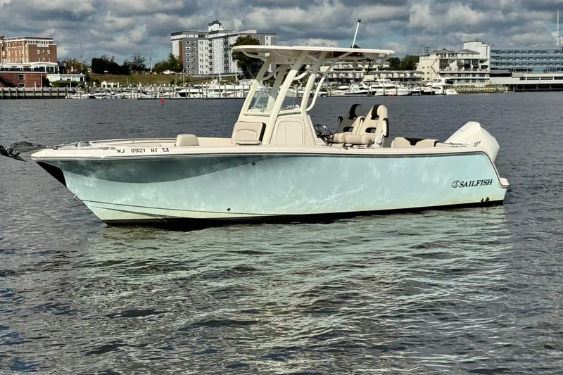 Slide: The Image of 2024 Sailfish 241 CC boat on calm water with cityscape background. - 5