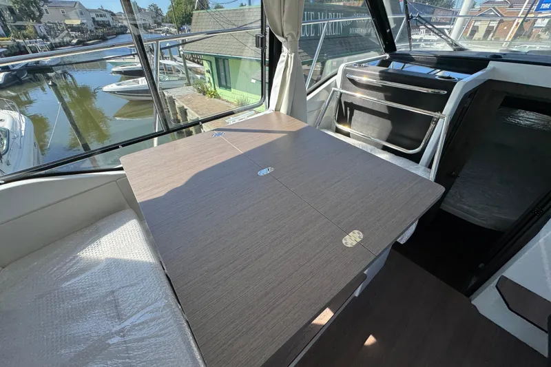 Slide: The Image of Interior of 2026 Jeanneau NC 895 Series 2 boat with dining table and marina view. - 10