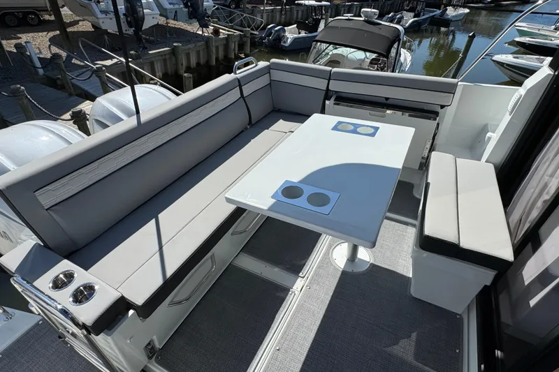 Slide: The Image of 2026 Jeanneau NC 895 Series 2 boat interior with seating and table in a marina setting. - 3