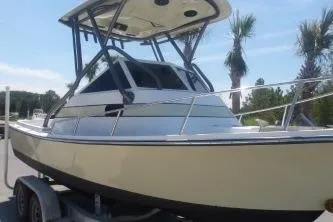 Slide: The Image of 1989 Shamrock 200 Cuddy boat on trailer, palm trees in background. - 0