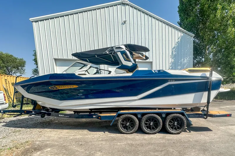 Slide: The Image of 2025 Nautique Super Air Nautique G25 Paragon boat on trailer, parked outdoors. - 3
