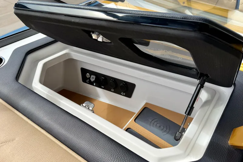 Slide: The Image of 2025 Nautique Super Air Nautique G25 Paragon storage compartment with charging ports and wireless charging pad. - 40