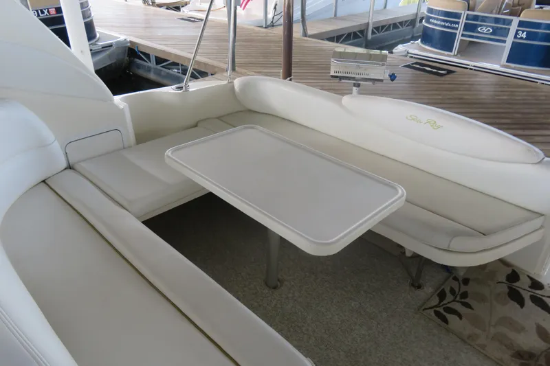Slide: The Image of 2001 Sea Ray 340 Sundancer interior with white seating and table, docked at marina. - 3