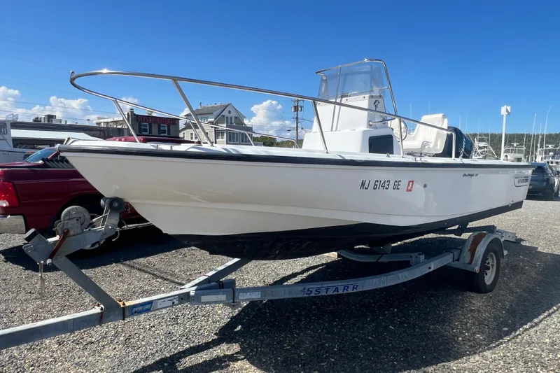 The Image of 1997 Boston Whaler Outrage 20 boat on trailer, parked outdoors under clear sky. - 1