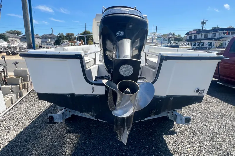Slide: The Image of 1997 Boston Whaler Outrage 20 boat with powerful outboard motor, parked on gravel. - 3