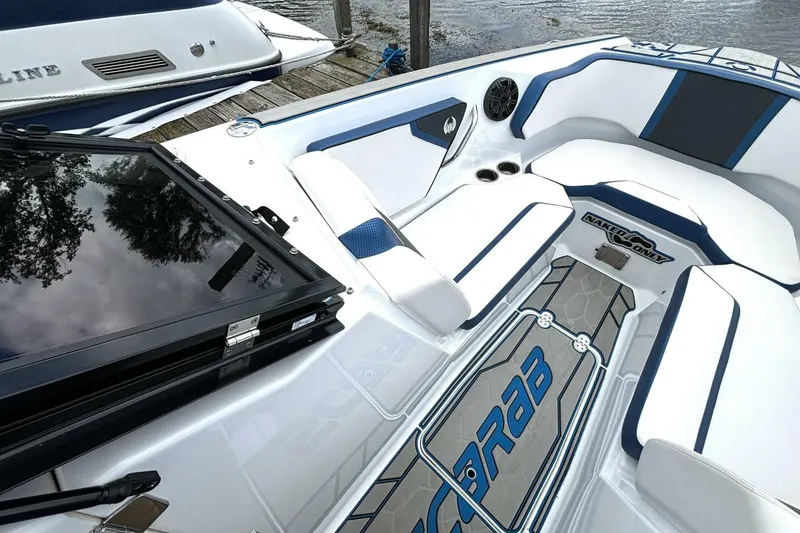 Slide: The Image of 2020 Scarab 255 ID Wake boat interior with white and blue seating, docked by water. - 27
