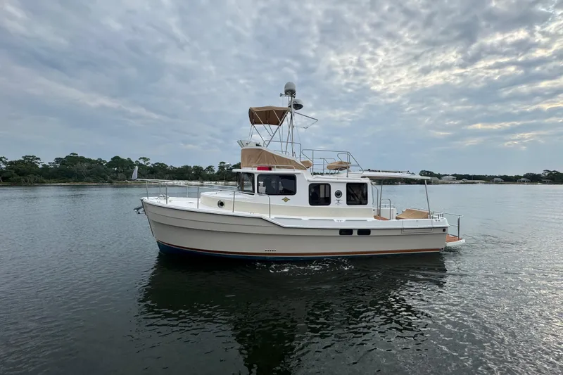 Slide: The Image of 2022 Ranger Tugs R-31 CB boat on calm water under cloudy sky. - 0