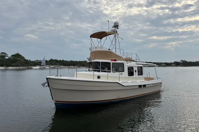 Slide: The Image of 2022 Ranger Tugs R-31 CB boat on calm water under cloudy sky. - 2