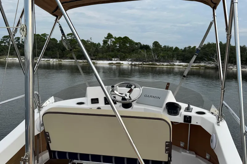 Slide: The Image of 2022 Ranger Tugs R-31 CB helm with Garmin navigation, overlooking serene water and shoreline. - 26