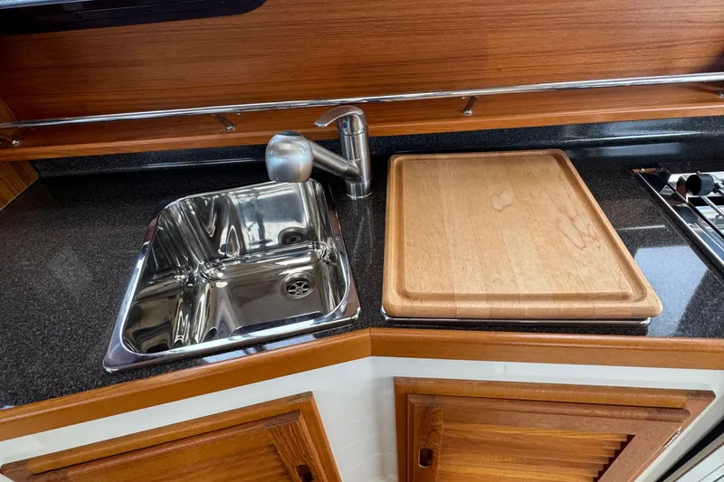 Slide: The Image of 2022 Ranger Tugs R-31 CB kitchen with stainless steel sink and wooden cutting board. - 51