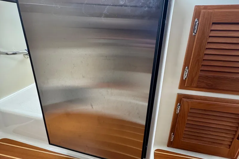 Slide: The Image of Interior of 2022 Ranger Tugs R-31 CB with stainless steel fridge and wooden cabinets. - 60