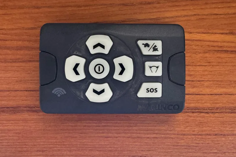 Slide: The Image of Remote control for 2022 Ranger Tugs R-31 CB, featuring directional and SOS buttons on wood surface. - 62