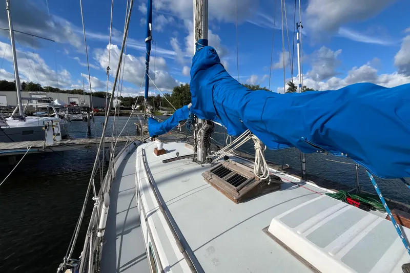 Slide: The Image of 1982 Tayana 37 sailboat deck with blue sail covers, docked at marina under blue sky. - 10