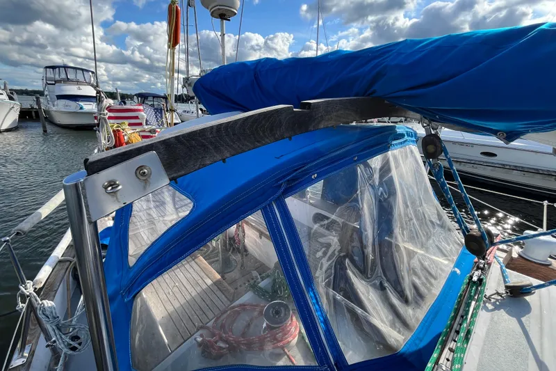 Slide: The Image of 1982 Tayana 37 sailboat with blue cover docked at marina under cloudy sky. - 14