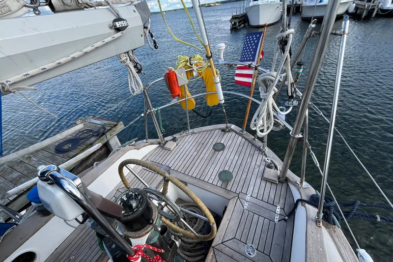 Slide: The Image of 1982 Tayana 37 sailboat deck with nautical equipment and American flag in marina. - 18