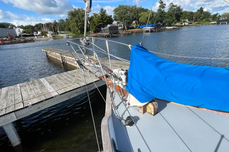 Slide: The Image of 1982 Tayana 37 sailboat docked by a wooden pier on a sunny day. - 2