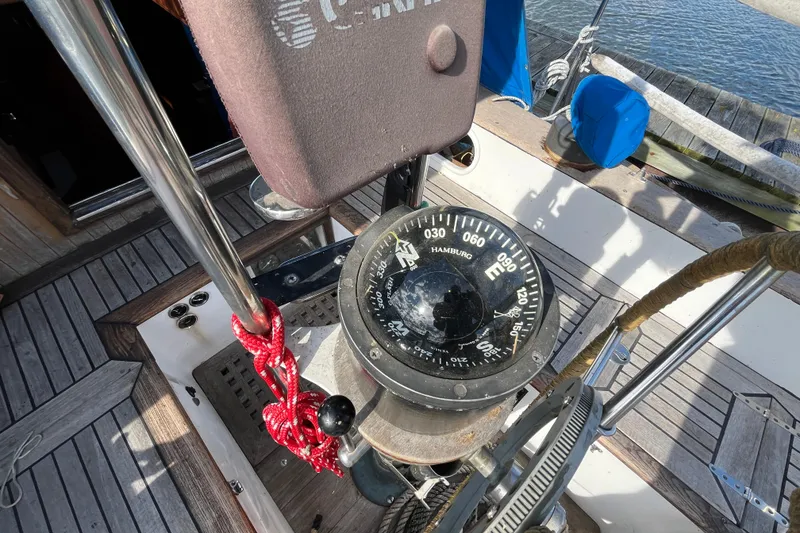 Slide: The Image of Compass on 1982 Tayana 37 sailboat deck, featuring wooden flooring and nautical equipment. - 22