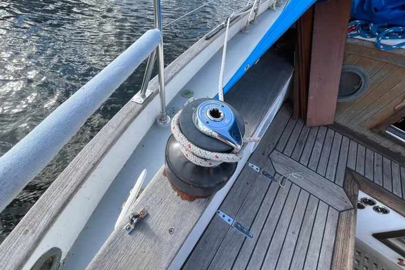 Slide: The Image of 1982 Tayana 37 sailboat deck with winch and rope, near water. - 23