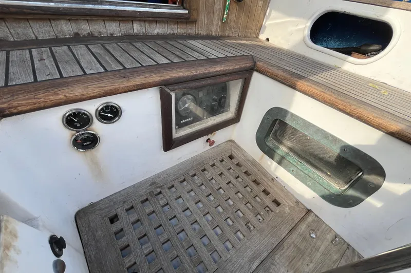 Slide: The Image of 1982 Tayana 37 cockpit with wooden flooring, gauges, and Yanmar engine panel. - 24