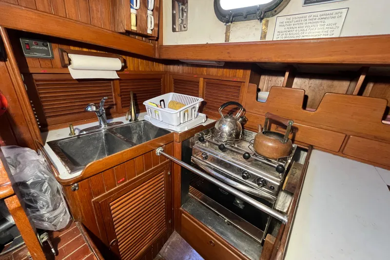 Slide: The Image of 1982 Tayana 37 yacht galley with stove, sink, and wooden cabinetry. - 29