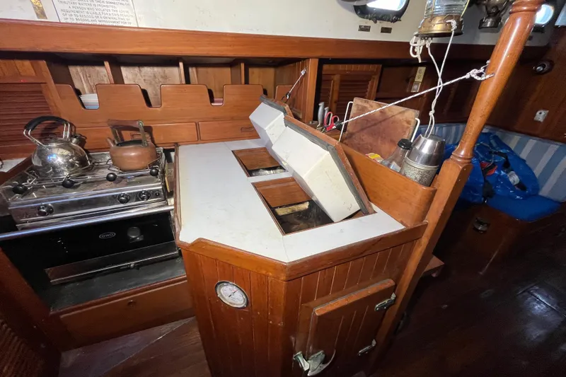 Slide: The Image of 1982 Tayana 37 yacht galley with stove, kettle, and wooden cabinetry. - 30