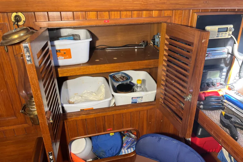 Slide: The Image of 1982 Tayana 37 interior with wooden cabinets, storage bins, and navigation equipment. - 39