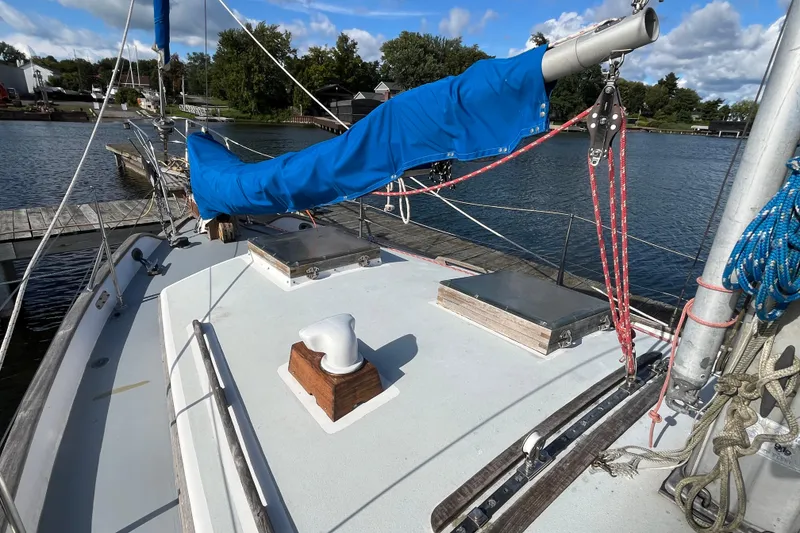 Slide: The Image of 1982 Tayana 37 sailboat deck with blue sail cover, docked by calm waters. - 4