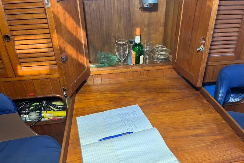 Slide: The Image of Interior of 1982 Tayana 37 sailboat with wooden cabinetry and open notebook. - 40