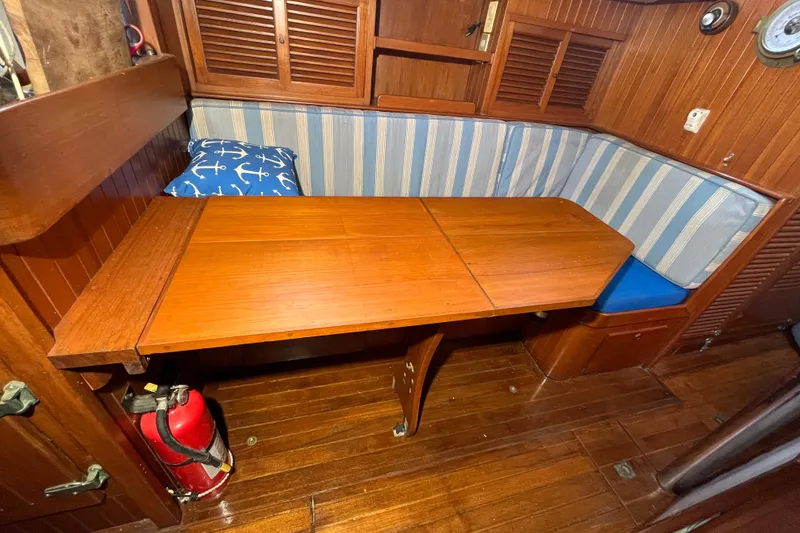 Slide: The Image of Cozy 1982 Tayana 37 yacht interior with wooden table, striped seating, and nautical decor. - 46
