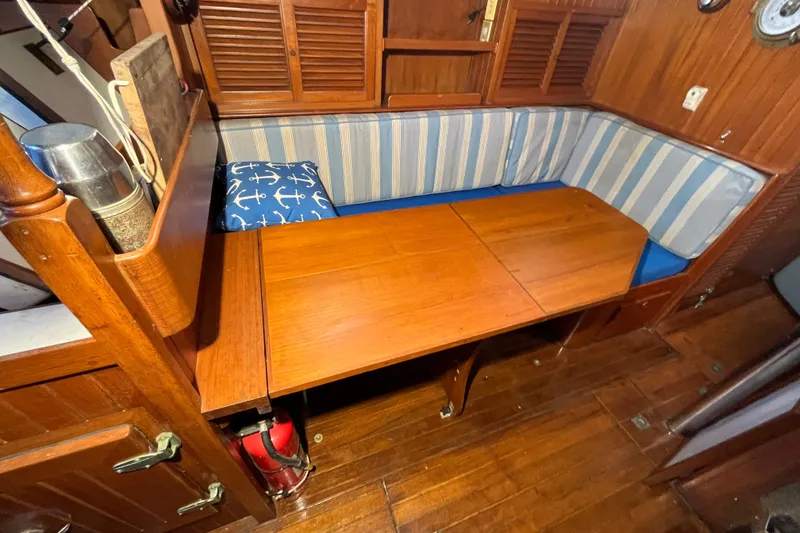 Slide: The Image of Cozy 1982 Tayana 37 sailboat interior with wooden table and striped seating. - 47